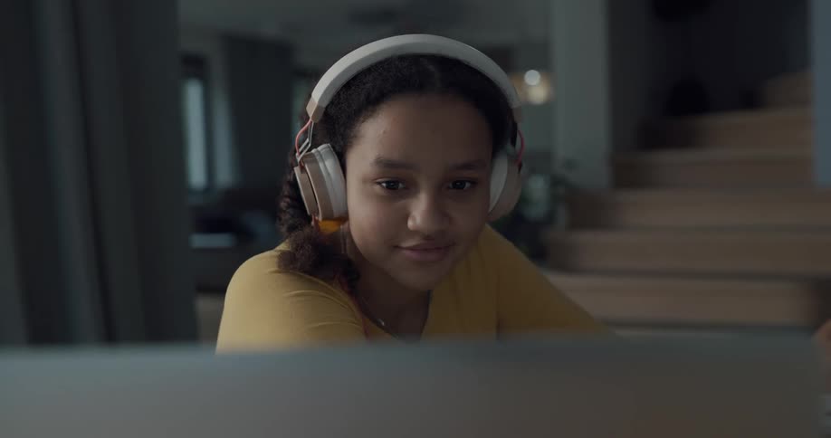 A young teenage girl video chats on her computer at home
