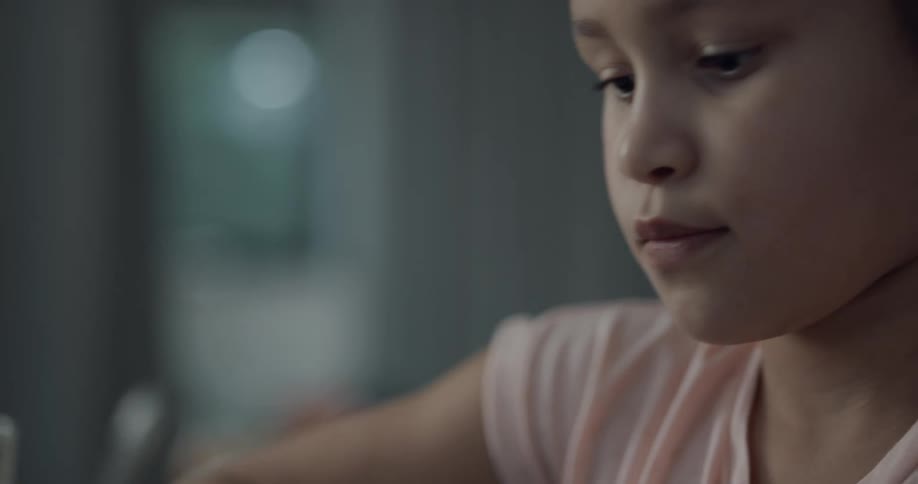 Young girl doing homework at the table in a room at home