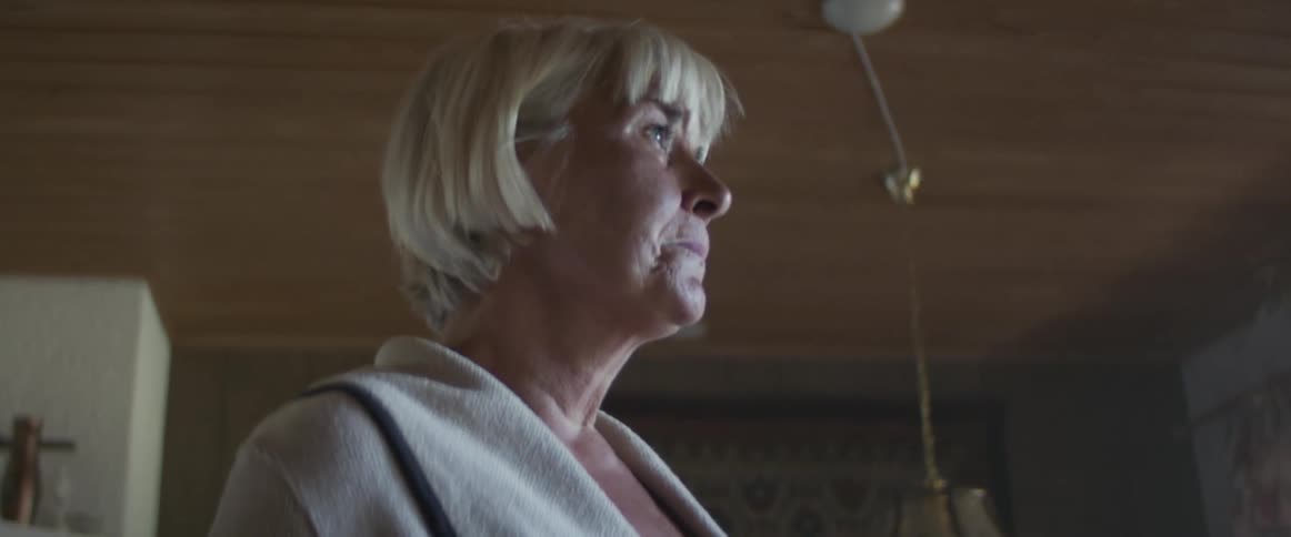 An elderly woman crying in her kitchen
