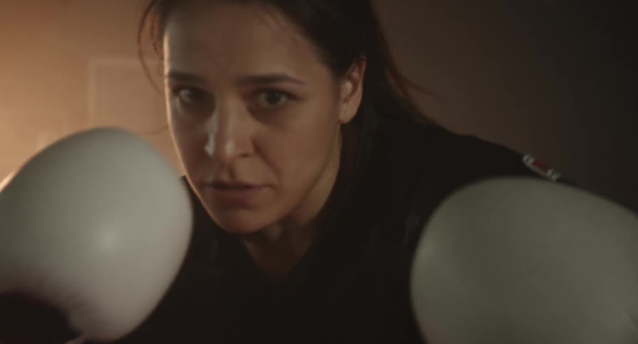 A woman wearing white gloves is shadow boxing
