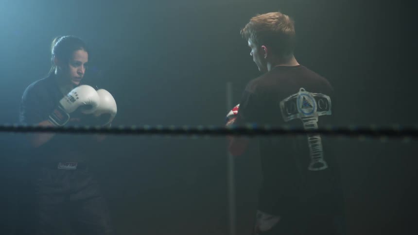 Two people are kickboxing in a ring