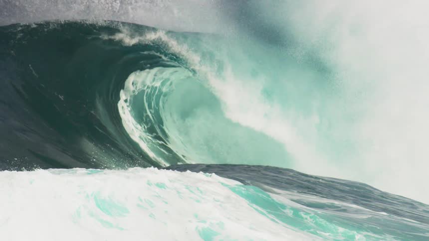 A man paddles out in to the ocean as a large waves moves forwards