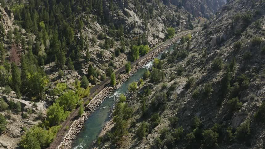 Aerial view of a river flowing at the bottom of a canyon next to a train track