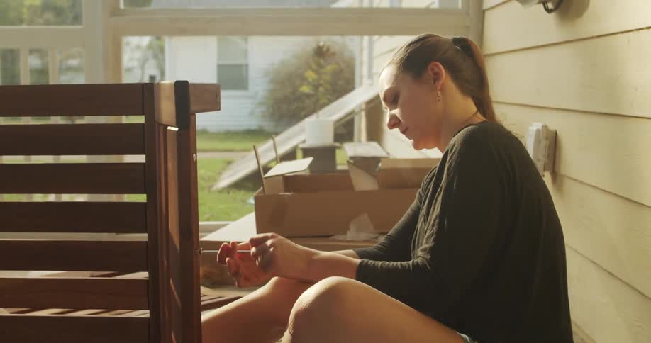 A woman puts furniture together at her home