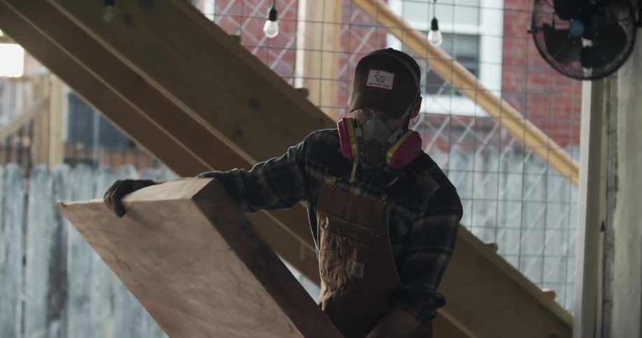 A man lowers wood on to a table to cut it