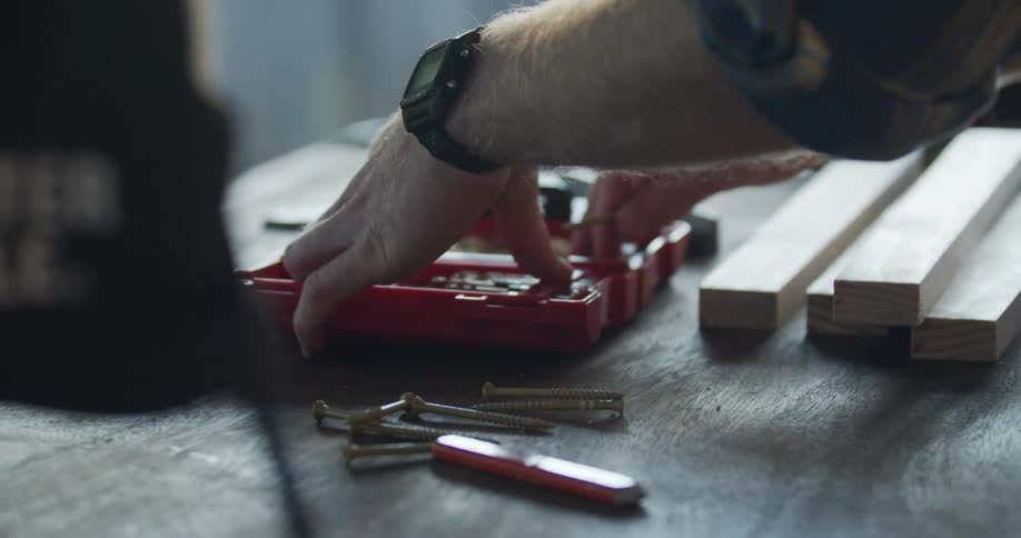 A man puts screws away after working with wood