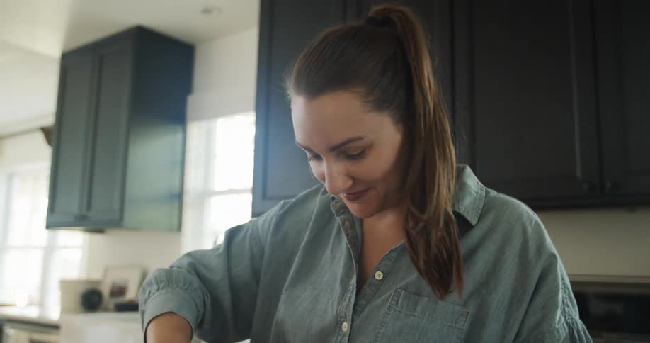 Smiling woman with pony tail works in kitchen