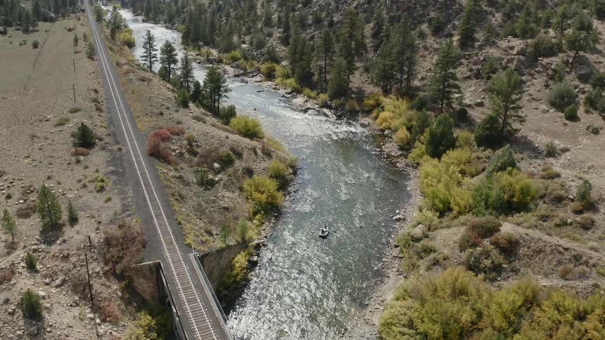 Two people float down a river that runs through a canyon on an inflatable boat
