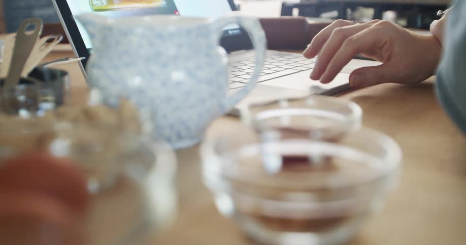 Person sits at wooden table scrolling using laptop pad