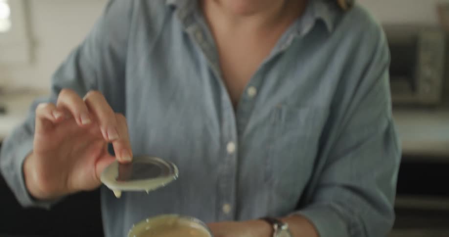 A woman at home scrapes the lid from a can of condensed milk against the container as she bakes