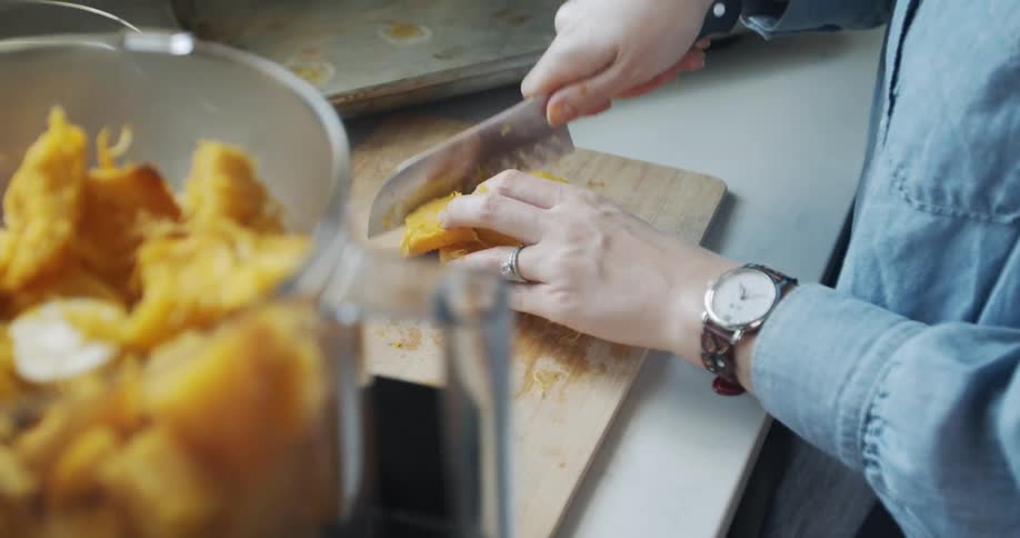 A woman cutting up food and putting it in blender