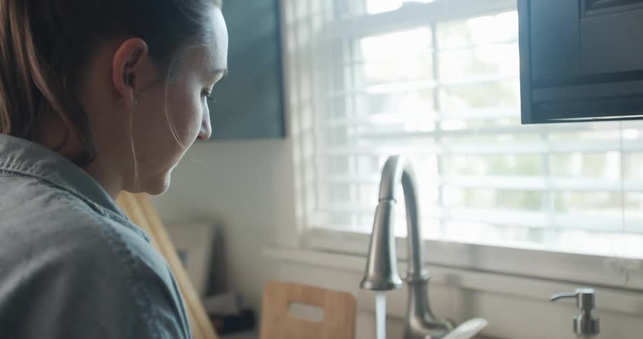 A woman washing dishes at home in the daytime