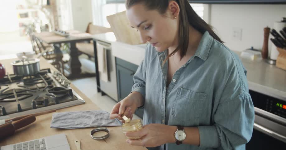 A caucasian woman measuring ingredients into a small bowl in the kitchen