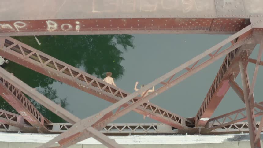 Two men jumping off a bridge into water