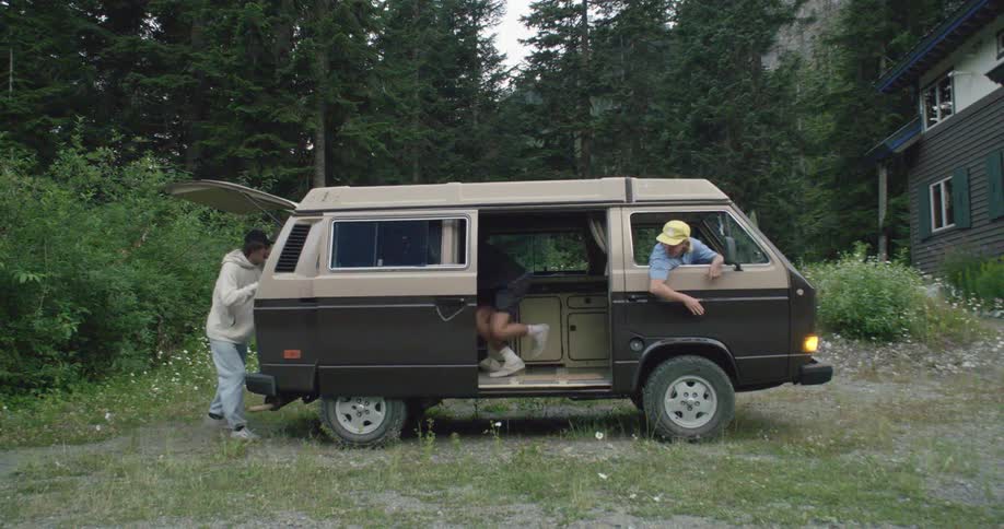 Group of friends run hurriedly to board a van parked outdoors