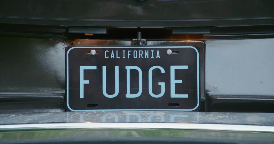 Close up of a novelty license plate on the silver car bumper