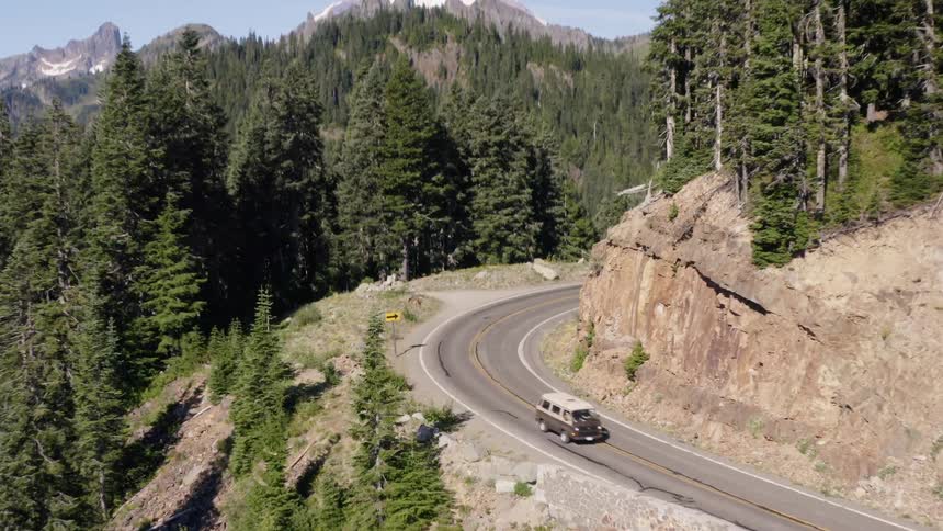 A van drives on a paved road on a mountain