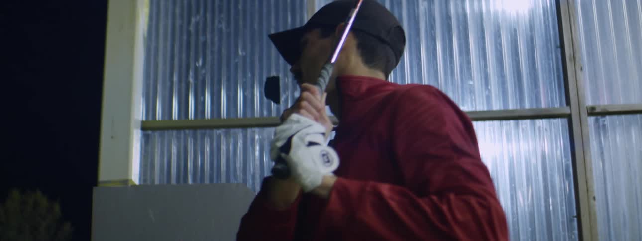 A man hits the golf ball at night