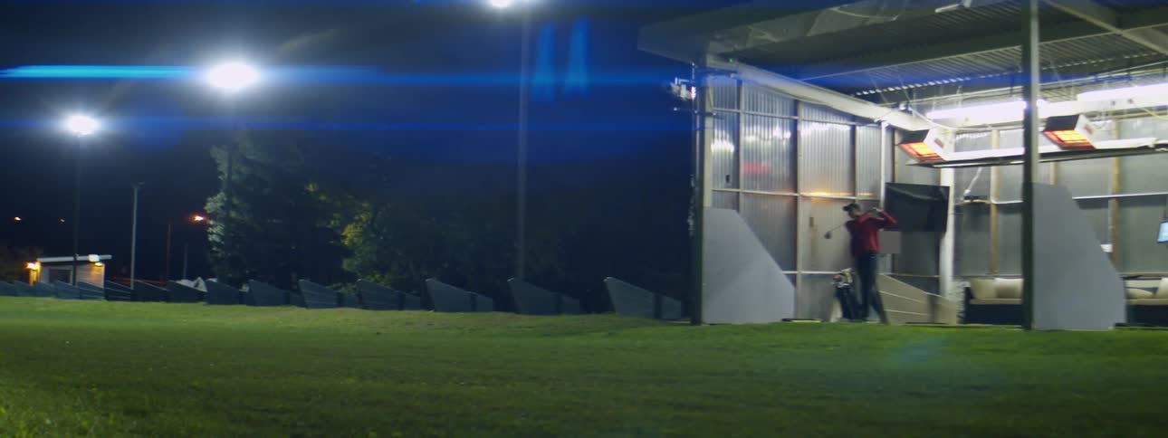 A man is driving golf balls on the driving range