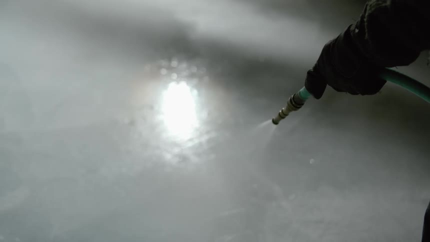 A person spraying down concrete