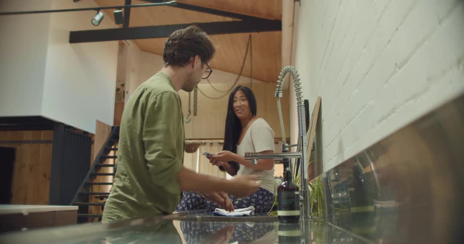 Man talks to woman sitting on counter while washing hands
