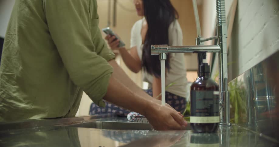 A man washes his hands as a woman talks to him