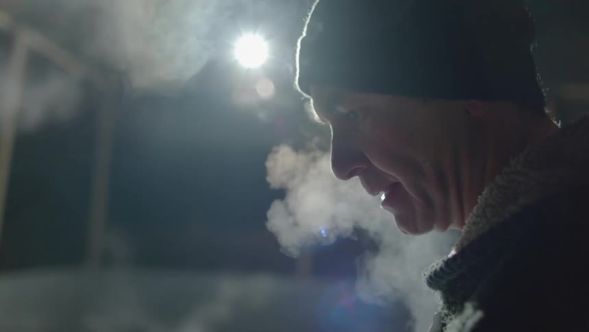 Man wearing a toque talks while white smoke moves around next to him