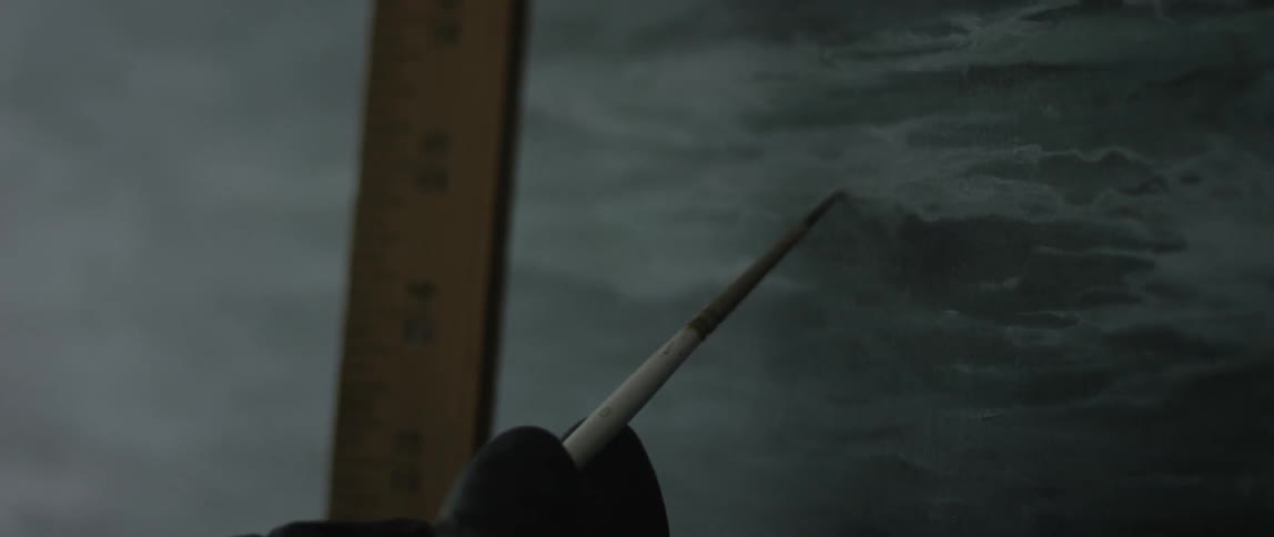 A person is painting with a ruler nearby