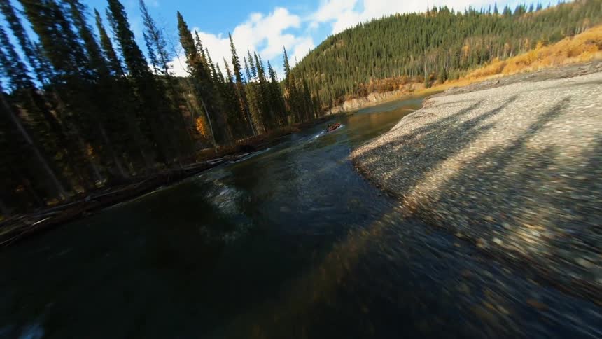 A person floats down a river in a canoe