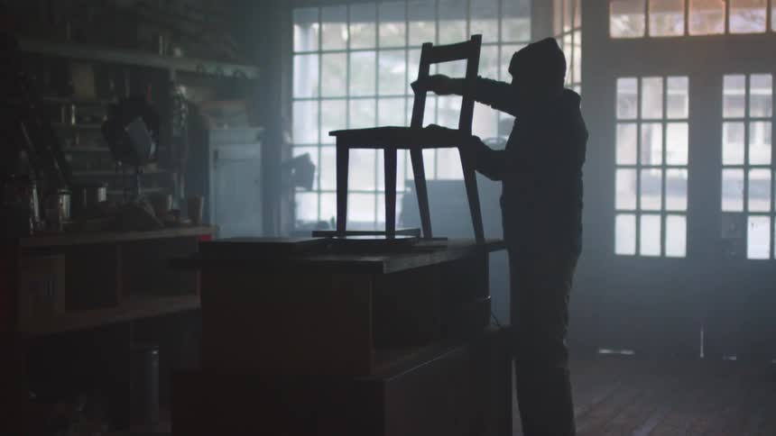 A carpenter in a store sands a chair