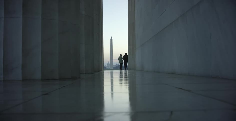 Two people standing in a corridor looking at a monument