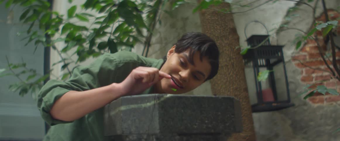 A woman smiles and touches the plant she planted and pats dirt down