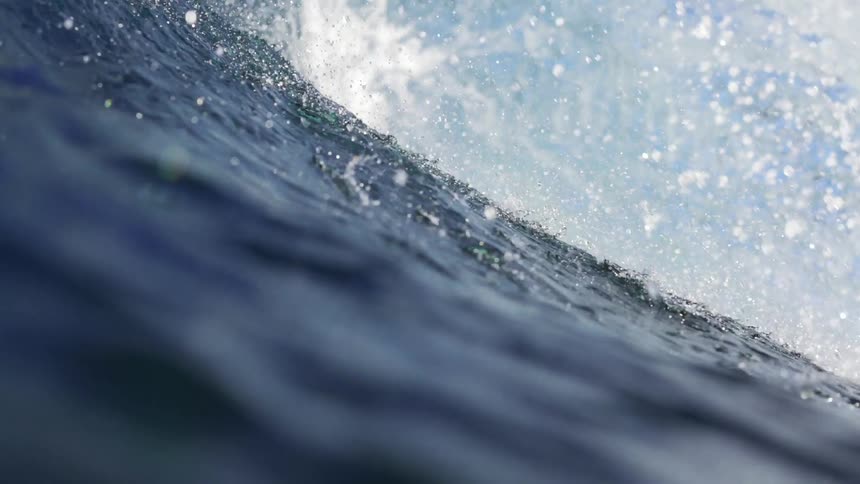 Huge ocean wave splashes as it rolls in