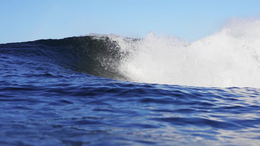 Blue ocean with crashing wave with a blue sky