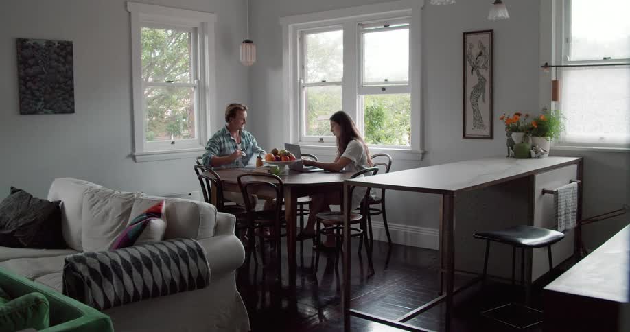 A man and woman sit at a dining table reviewing paperwork