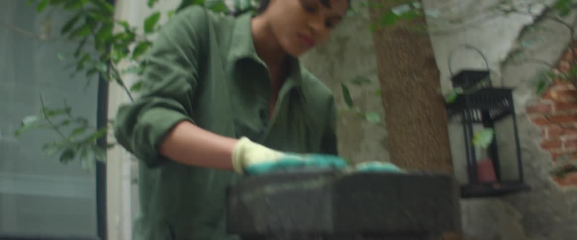A woman outside her home plants in a planter