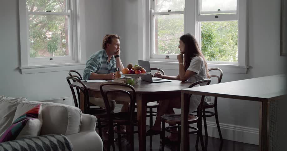 Young couple sitting at the table working and talking in the kitchen at home