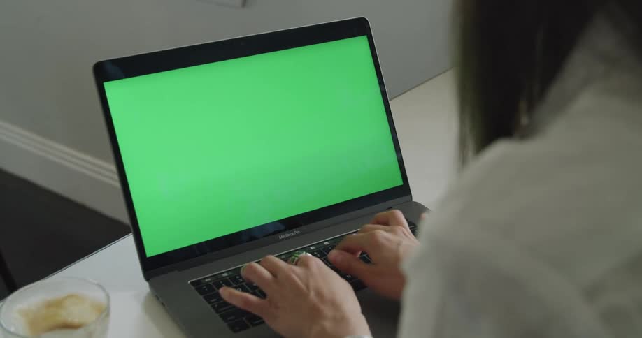 A woman sitting at a table typing on a laptop