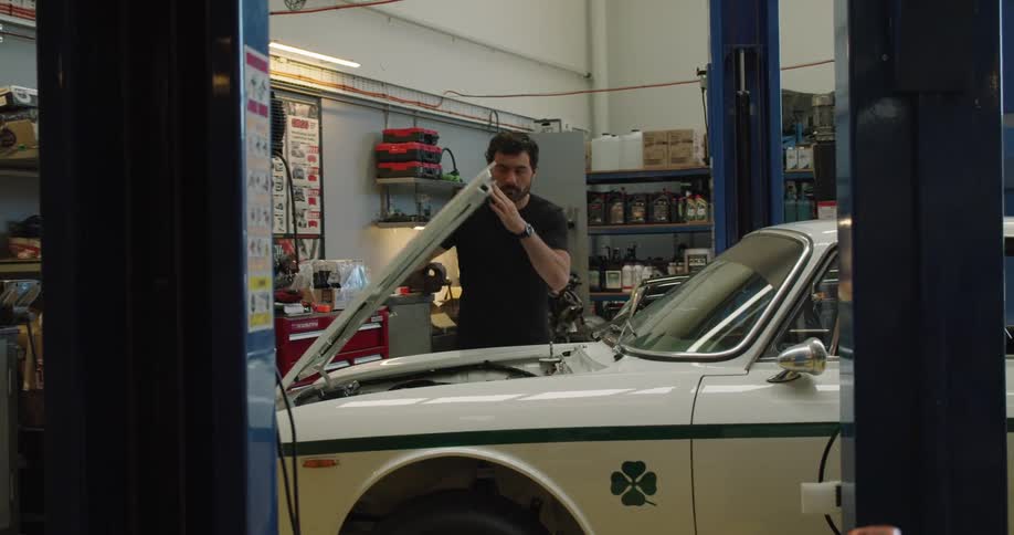 Mechanic opening the hood of a car to check the engine in a shop