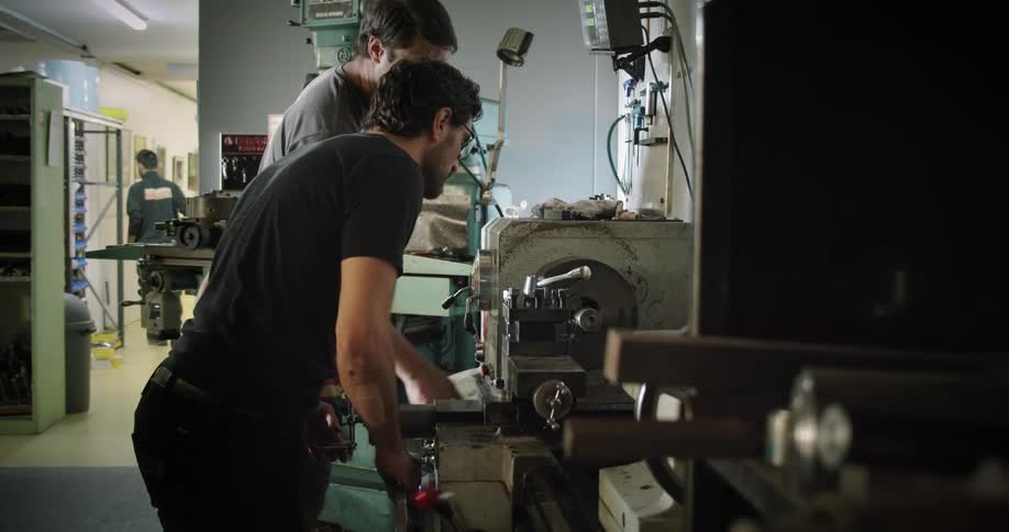 Two men in a workshop look at a machine