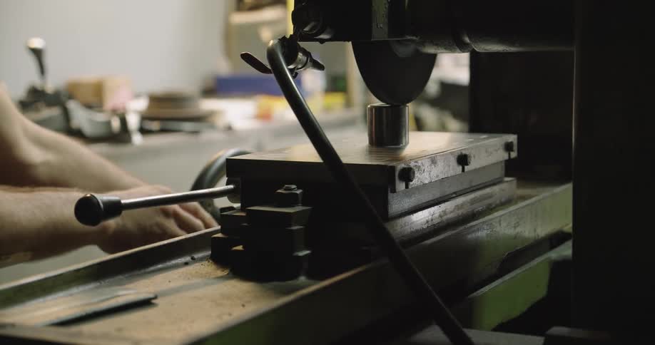 Worker operating a machine over a workbench in a workshop