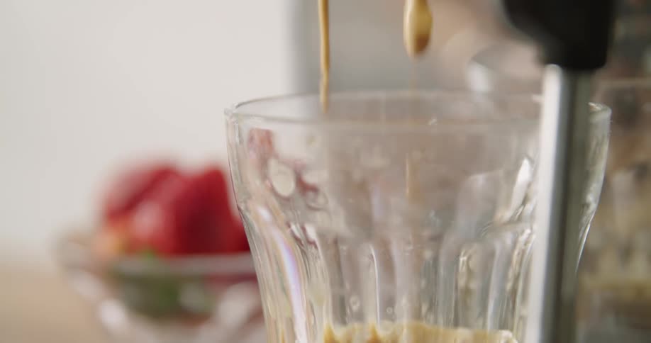 Cappuccino dripping from a cappuccino machine into a glass