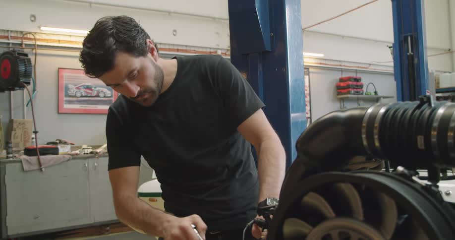A male mechanic working on automobile engine with a socket wrench