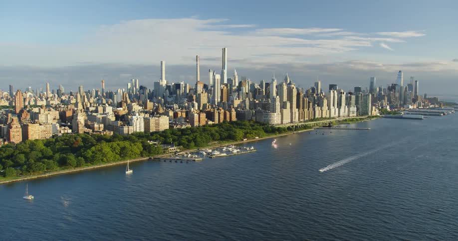 An aerial view of boats on the water and a city skyline on the shore
