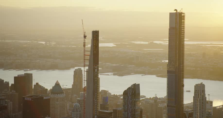 A pair of skyscrapers under construction loom over a metropolis in the evening