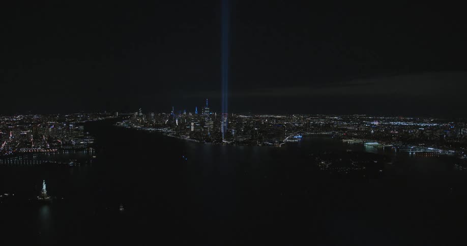 A tall blue beam of light shoots up from a downtown building next to the water