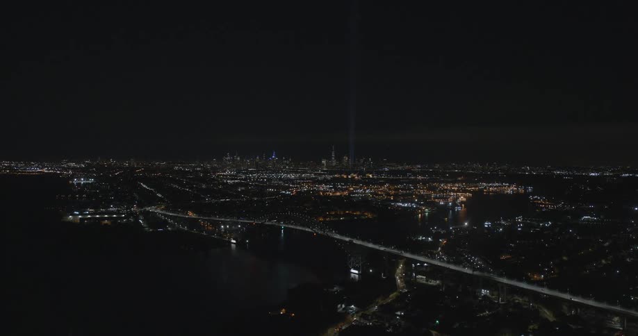Pillars of light reach into the nighttime sky over a metropolis at night