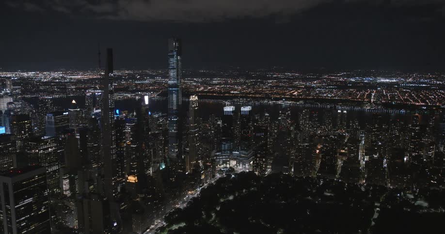 Aerial view of skyscrapers and buildings downtown with lights on at nighttime