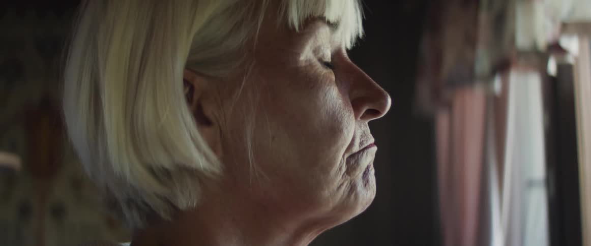 A woman is standing indoors staring out a window