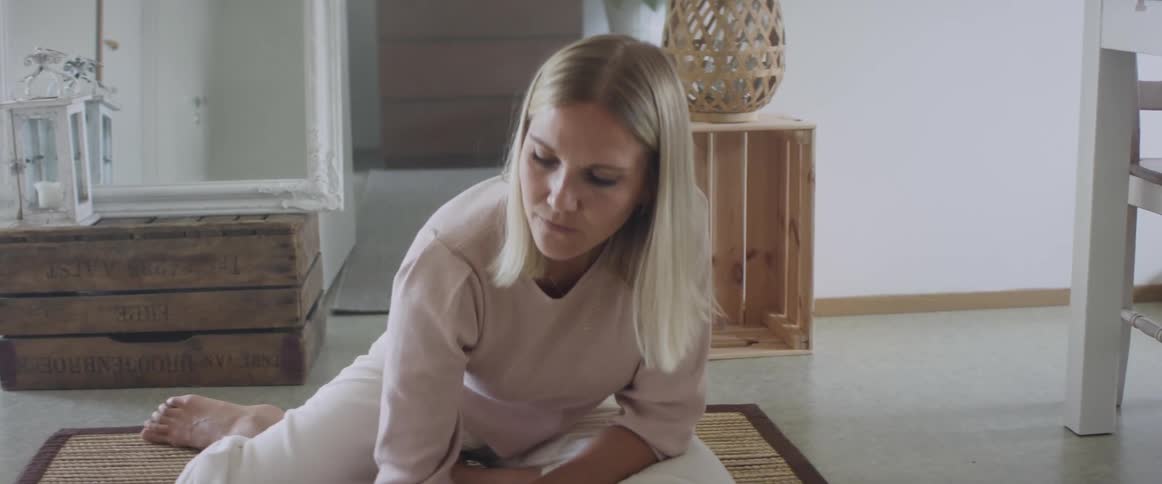 Blonde woman sitting on the ground writes things down in a notebook in the living room